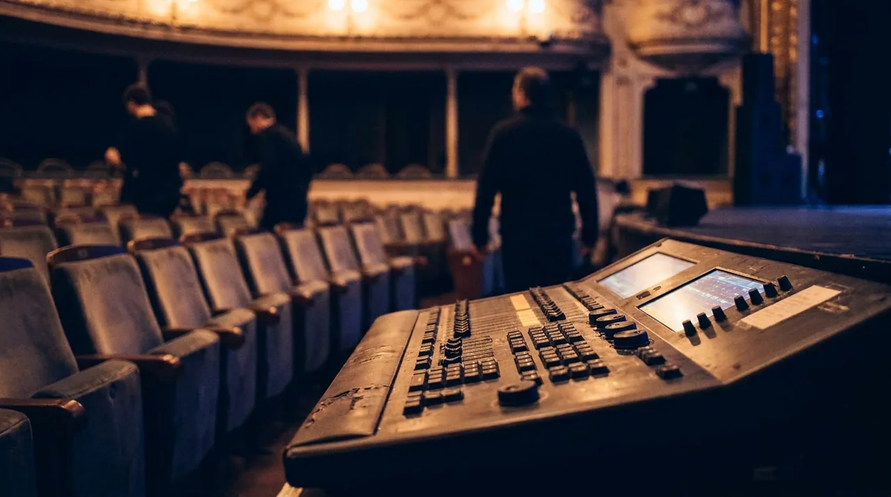 Coulisses d'une salle de spectacle vide, régie technique éclairée en fin de représentation